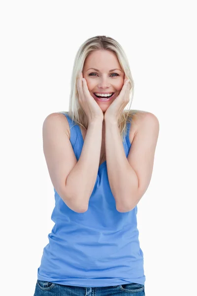 Happy blonde woman showing her surprise by placing her hands on — Stock Photo, Image