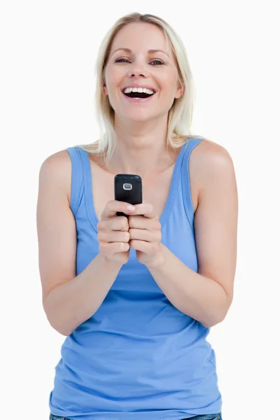Mulher loira rindo ao enviar uma mensagem com seu telefone celular — Fotografia de Stock