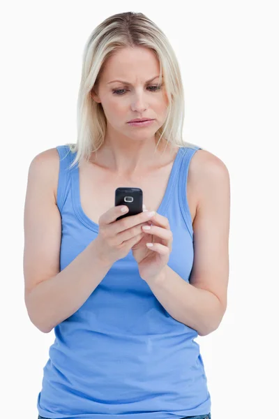 Mulher séria olhando para seu telefone celular enquanto se concentra — Fotografia de Stock
