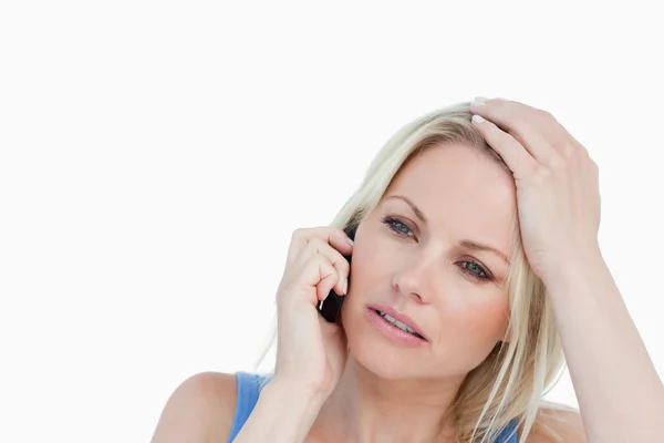 Allvarliga blond kvinna ringer samtidigt som hennes hand på hennes huvud — Stockfoto