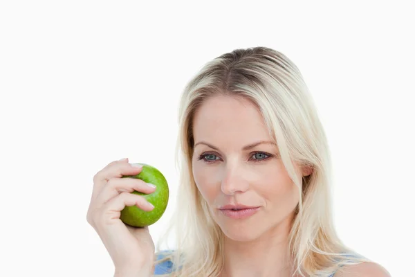 Thoughtful blonde woman holding a green apple — Stock Photo, Image