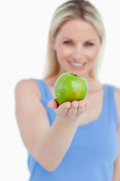 Delicious green apple held by a smiling blonde woman — Stock Photo, Image