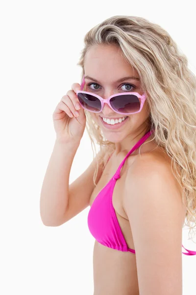 Улыбающийся привлекательный подросток смотрит на свои солнечные очки — стоковое фото