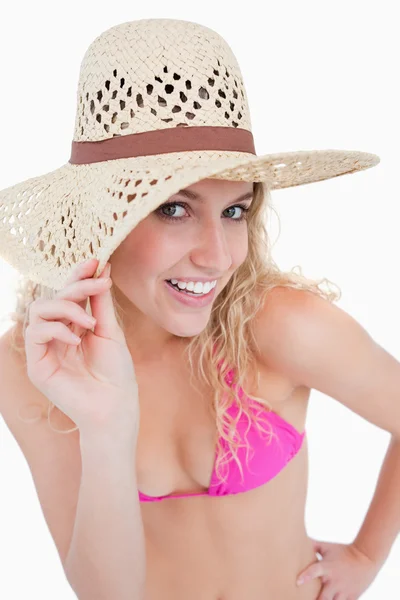 Jonge blonde vrouw kijken naar de camera terwijl haar hoed b — Stockfoto