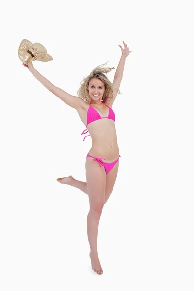 Smiling young blonde woman raising her arms while holding her ha — Stock Photo, Image