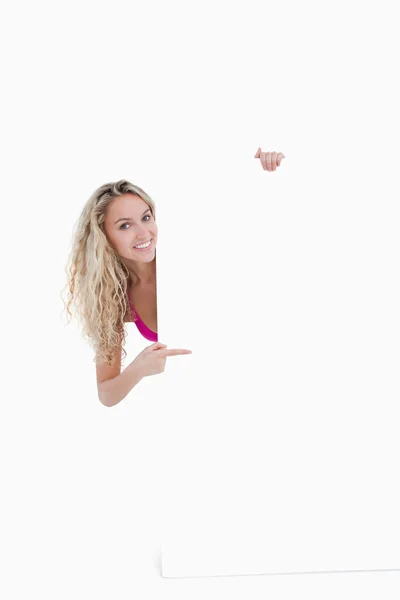 Teenage girl beaming while pointing her finger at a blank poster — Stock Photo, Image