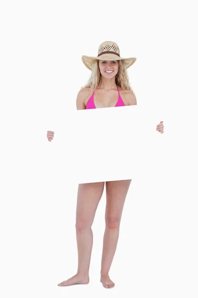 Adolescente sorridente em um maiô rosa segurando um pôster em branco — Fotografia de Stock