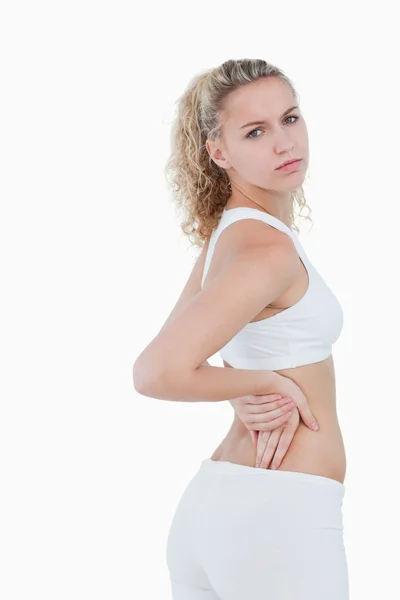 Молодая серьезная женщина показывает боль в спине — стоковое фото