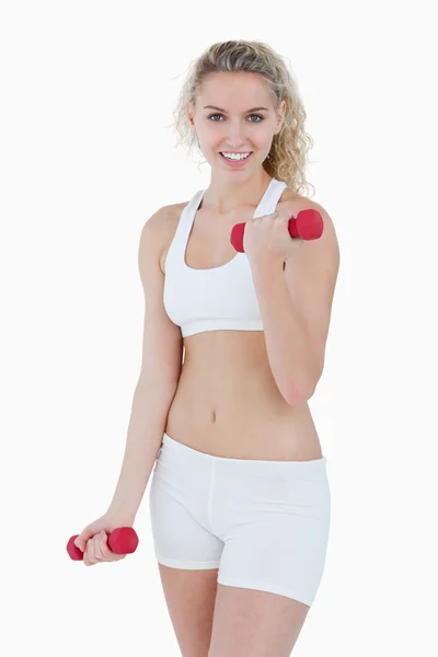 Smiling teenager looking at the camera while lifting weights — Stock Photo, Image