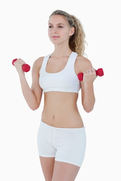 Concentrated attractive teenager lifting red weights — Stock Photo, Image
