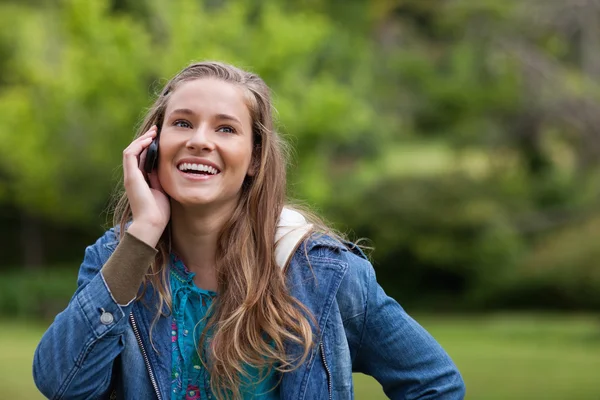 Adolescente usando su teléfono móvil mientras muestra una gran sonrisa — Foto de Stock