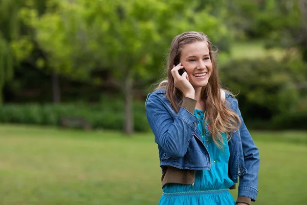 Девушка-подросток, стоящая в сельской местности, разговаривая по телефону. — стоковое фото