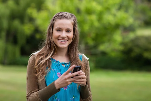 Genç kızın cep telefonu kullanarak mesaj gönderirken gülümseyen — Stok fotoğraf