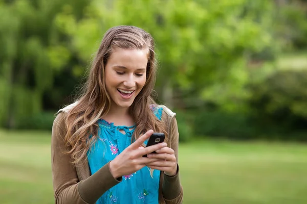 Menina adolescente feliz recebendo um texto em seu telefone celular — Fotografia de Stock
