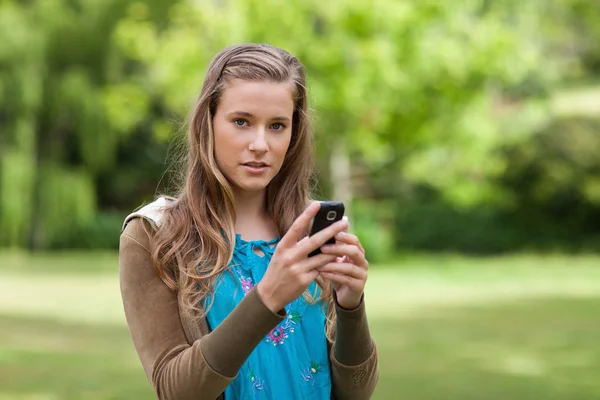 Девочка-подросток отправляет текст, глядя в камеру — стоковое фото