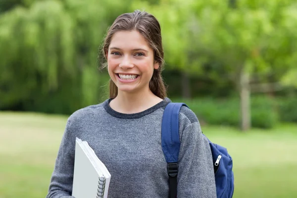 Junger glücklicher Erwachsener, der von der Schule zurückkommt und ein Notizbuch in der Hand hält — Stockfoto