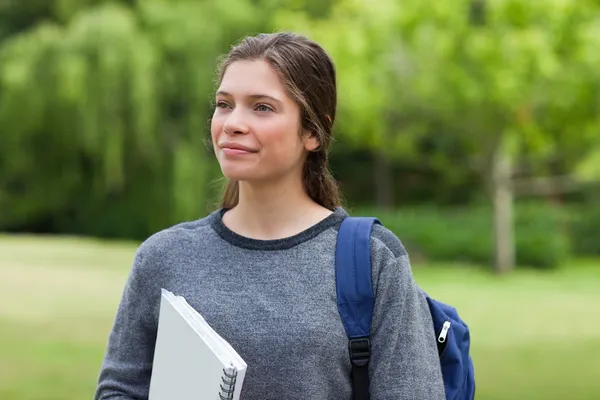 stock image Young smiling woman looking far away while standing in a park wi