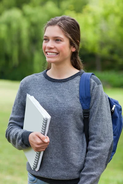Junge glückliche Frau mit strahlendem Lächeln, während sie ein Notizbuch in der Hand hält — Stockfoto