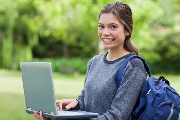 Jovem feliz segurando seu laptop enquanto sorri na frente do th — Fotografia de Stock
