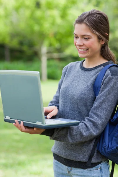 Estudante feliz olhando para a tela de seu laptop enquanto está de pé — Fotografia de Stock