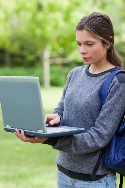 Estudiante serio escribiendo en su computadora portátil mientras está de pie en un —  Fotos de Stock
