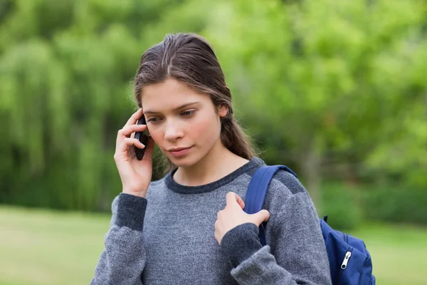 Doordachte jong meisje met behulp van haar mobiele telefoon terwijl de uitvoering van haar — Stockfoto