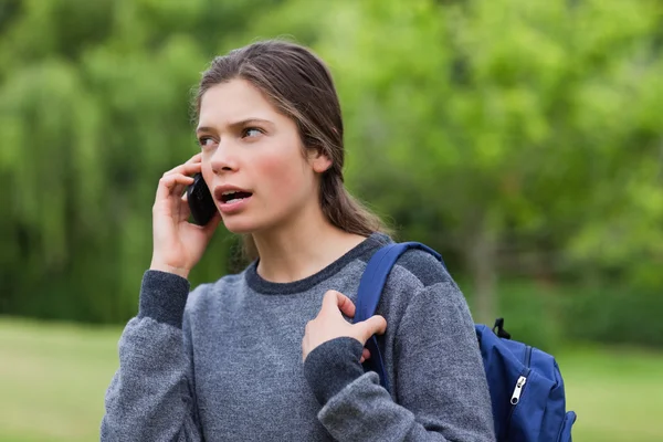 Giovane ragazza calma parlando al telefono, mentre guardando verso la s — Foto Stock