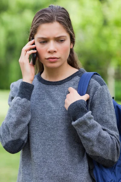 Serious student looking down while talking on the phone — Stock Photo, Image