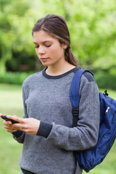 Joven chica seria enviando un mensaje de texto de pie en el país — Foto de Stock
