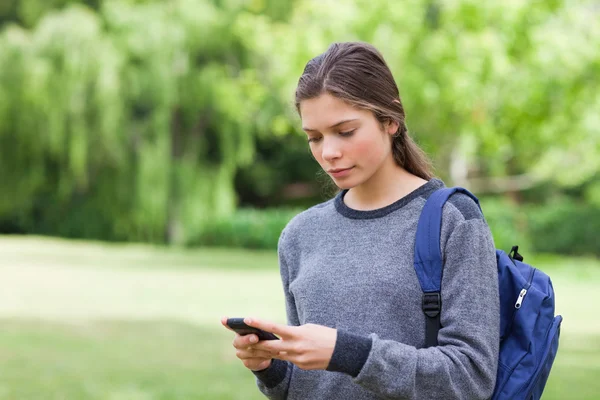 Joven chica tranquila usando su teléfono móvil para enviar un mensaje de texto — Foto de Stock
