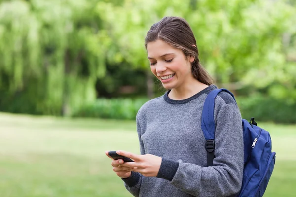 Adolescente souriante utilisant son téléphone portable tout en recevant un texte — Photo