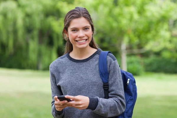 Junge lächelnde Frau schaut in die Kamera, während sie einen Text sendet — Stockfoto