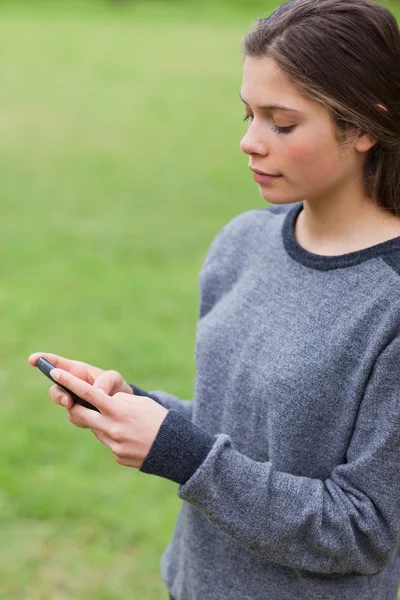 Junges ernstes Mädchen sendet mit ihrem Handy einen Text — Stockfoto