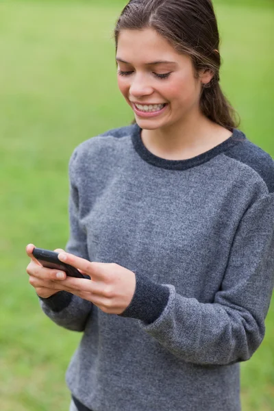 Young girl showing a beaming smile while sending a text — Stock Photo, Image