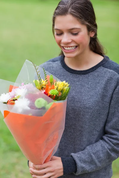Smiling teenage receiving a bunch of flowers — Stock Photo, Image