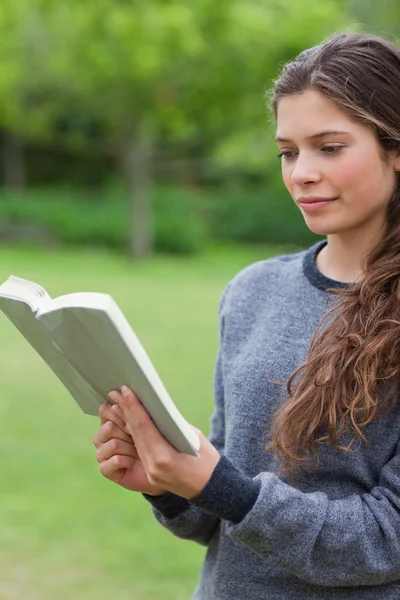 Молодая расслабленная девушка читает книгу в парке — стоковое фото