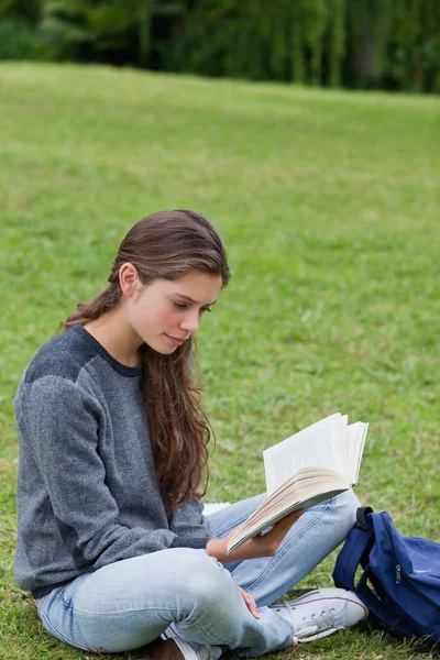 Νεαρή γυναίκα, διασχίζοντας τα πόδια της ενώ την ανάγνωση ενός βιβλίου — Φωτογραφία Αρχείου