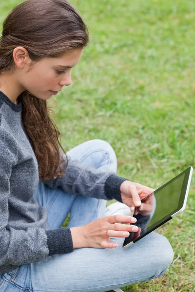 Junges lächelndes Mädchen sitzt im Schneidersitz und berührt ihren Tisch — Stockfoto