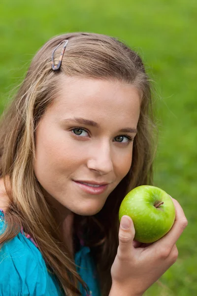 Atraktivní mladá dívka drží lahodné zelené jablko, zatímco stan — Stock fotografie