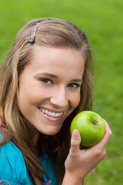 Atraktivní mladá dívka jíst zelené jablko v parku — Stock fotografie