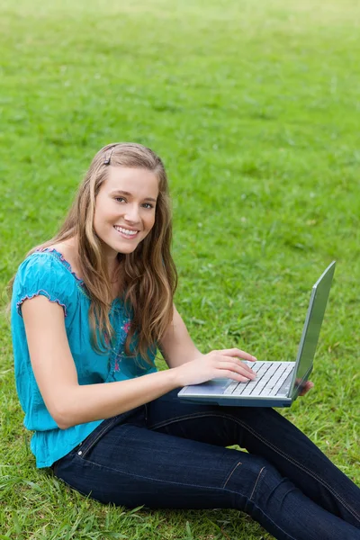 Young attractive girl looking at the camera while using her lapt — Stock Photo, Image