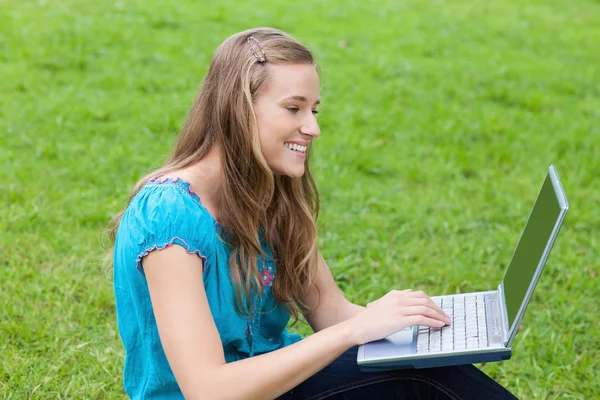 Молодая привлекательная девушка смотрит на свой ноутбук, сидя в — стоковое фото