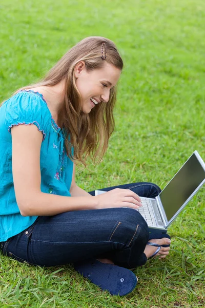 Young smiling woman sitting cross-legged in the countryside with — Stock Photo, Image
