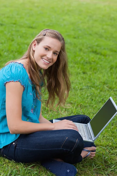 Usmívající se dívka při pohledu na fotoaparát při používání její laptop — Stock fotografie