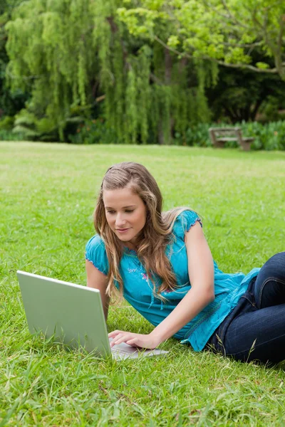Młoda dziewczyna zrelaksowany leżącego na boku podczas pracy na jej laptopie — Zdjęcie stockowe