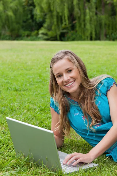 Ung flicka tittar på kameran när du använder sin laptop och smil — Stockfoto