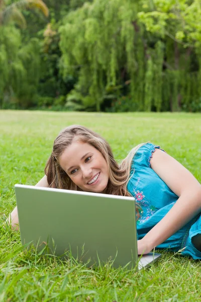 Ung kvinna visar ett stort leende liggande på sidan i en p — Stockfoto