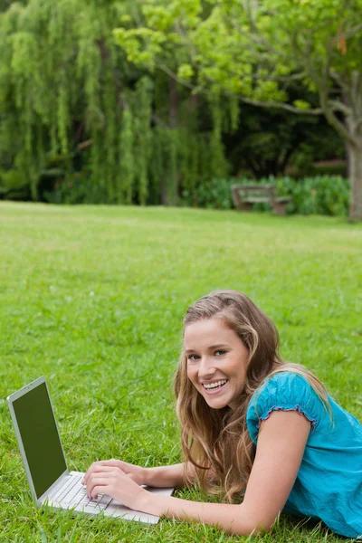 Giovane ragazza ridendo mentre digita sul suo computer portatile — Foto Stock