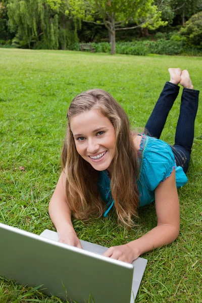 Lachende tienermeisje kijken naar de camera terwijl liggend op de gr — Stockfoto