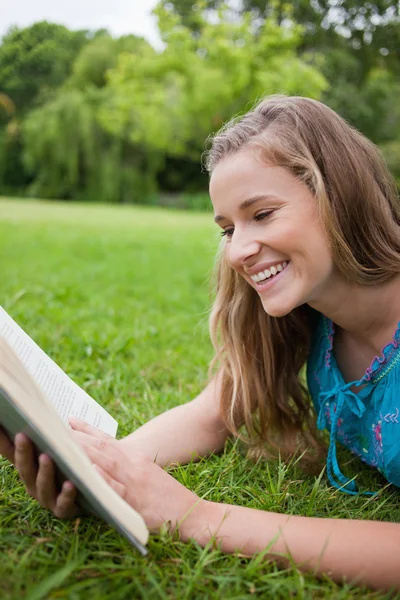 Молода дівчина читає книгу в парку під час сміху — стокове фото